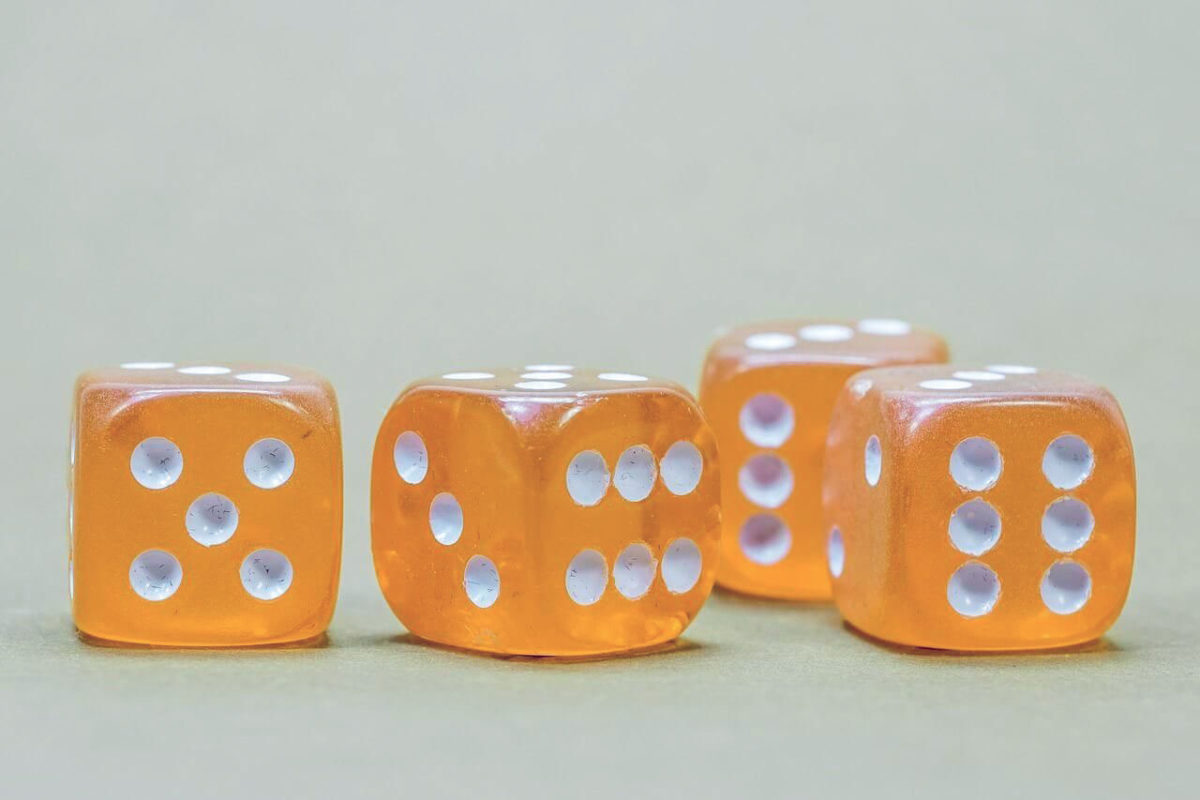 Vier Orangefarbene Würfel als Symbolbild für Glücksspiel