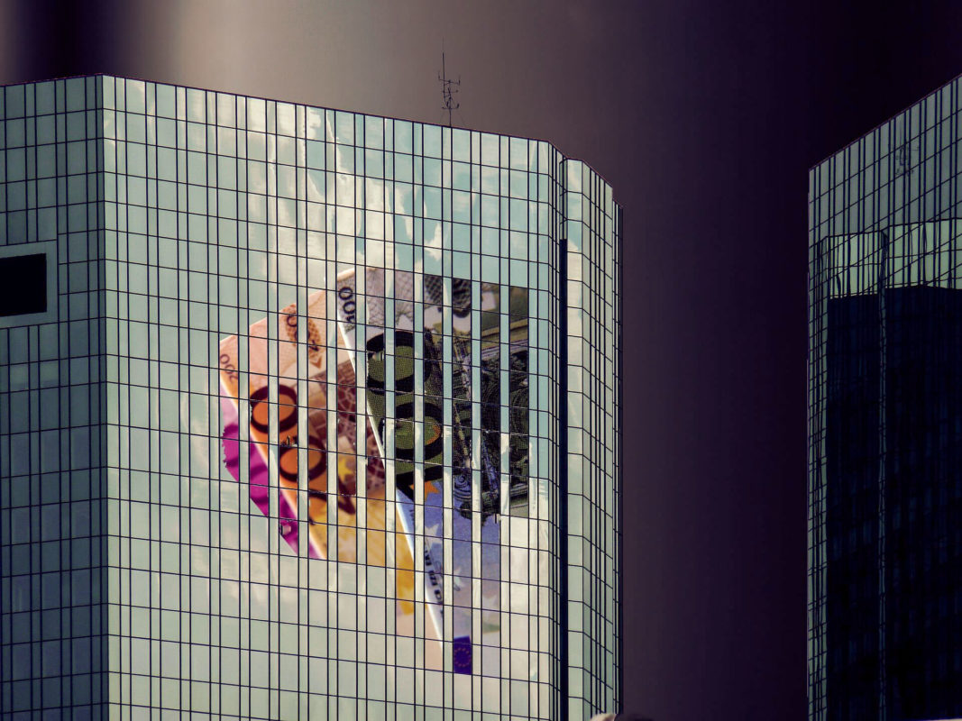 Ansicht eines verglasten Bankgebäudes, in welchem sich Euro-Geldscheine spiegeln