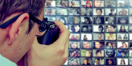 Mann mit Fotoapparat fotografiert eine Wand, welche zahlreiche Personen-Fotos zeigt.