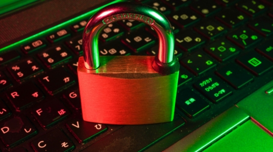 Rotes Vorhängeschloss auf einer schwarzen Computertastatur als Symbol für IT-Sicherheit